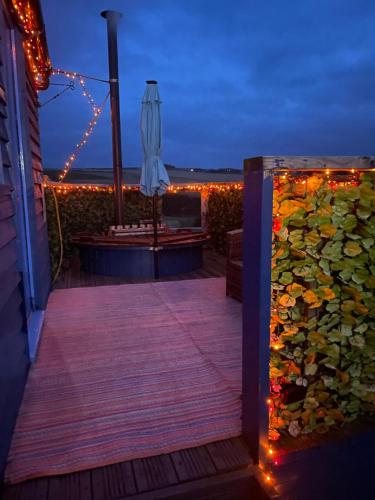 a deck with an umbrella and lights at night at Croft B&B Accommodation With Hot Tub in Gamrie