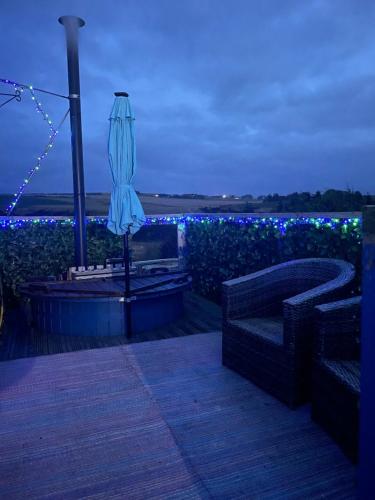um pátio com um guarda-sol e um jardim com luzes azuis em Croft B&B Accommodation With Hot Tub em Gamrie