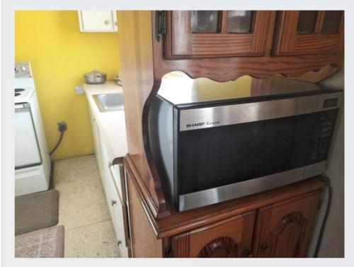 a microwave sitting on top of a wooden cabinet in a kitchen at Chelsea Manor in Kingston