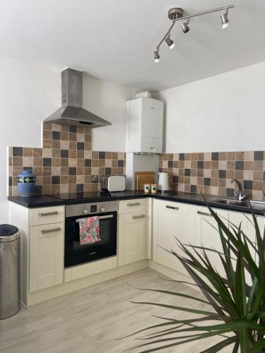 a kitchen with white cabinets and a stove top oven at Above the Bay - Enclosed garden apartment with parking in Penzance