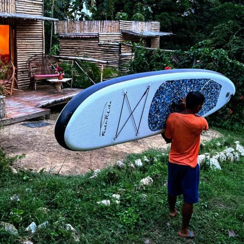 a man holding a surfboard on his head at Laguna Rosa Glamping in Coveñas