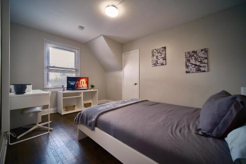 a bedroom with a bed and a desk and a television at Hamilton Chic Retreat - Comfy Beds - Garden - Pool in Hamilton