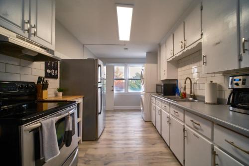 a kitchen with white cabinets and stainless steel appliances at Hamilton Mountain Plaza - King Bed - Free Parking in Hamilton
