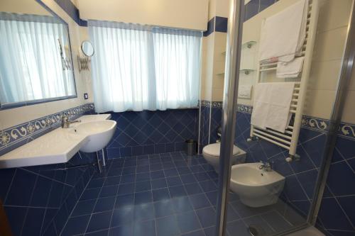 a blue tiled bathroom with two sinks and a toilet at Angelina Residence in Maiori