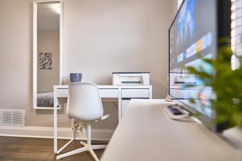 a white desk with a chair and a television at Hamilton Chic Retreat - Comfy Beds - Garden - Pool in Hamilton