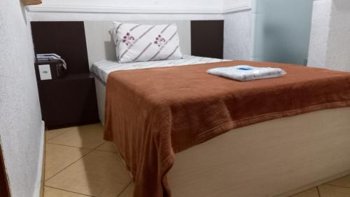 a bed with a brown blanket on top of it at Hotel Tenda Brigadeiro SP in Sao Paulo