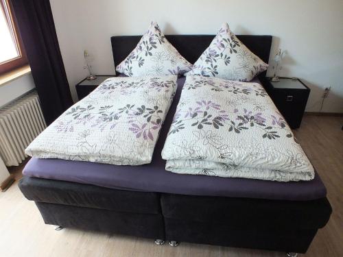 a bed with two pillows on top of it at Gästehaus Müller in Bad Schonborn