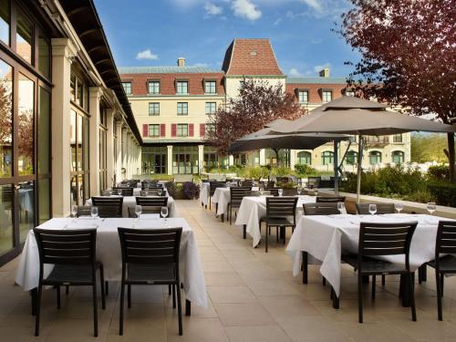 a restaurant with white tables and chairs and umbrellas at Radisson Blu Hotel Paris, Marne-la-Vallée in Magny-le-Hongre