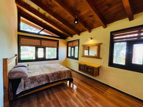 a bedroom with a bed in a room with windows at Cabaña La Esperanza in Mazamitla