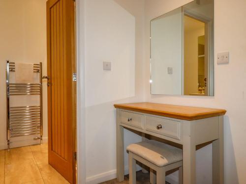 a bathroom with a vanity with a mirror and a stool at 12 Horizon View in Liskeard