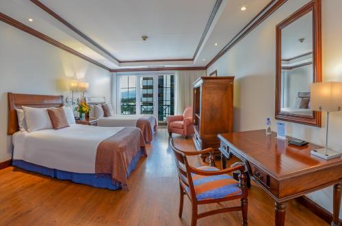 ein Hotelzimmer mit 2 Betten, einem Schreibtisch und einem Schreibtisch in der Unterkunft Hotel Casa Veranda Guatemala in Guatemala