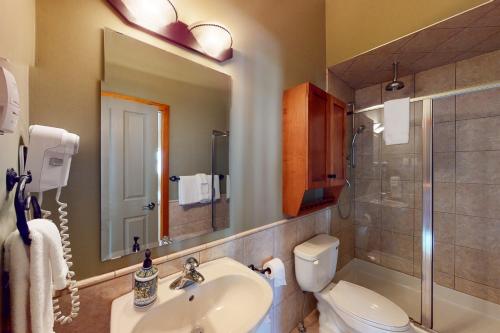 een badkamer met een wastafel, een toilet en een spiegel bij Blacksmith Lodge 2 in Big White