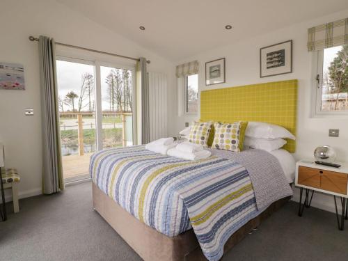 a bedroom with a large bed with a yellow headboard at 11 Meadow Retreat in Liskeard