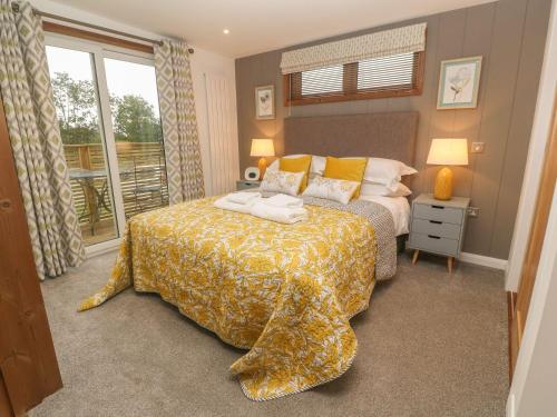 a bedroom with a bed with a yellow blanket at 12 Meadow Retreat in Liskeard