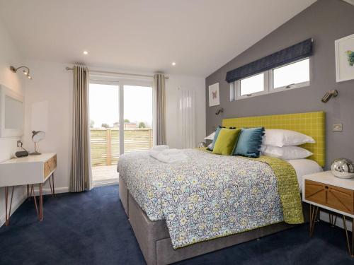 um quarto com uma cama com uma cabeceira amarela e uma janela em 19 Meadow Retreat em Liskeard