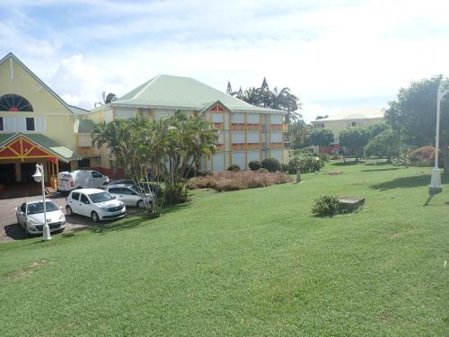 a large yard with cars parked in front of a building at Ti Kaz Emeraude - Mer, soleil et sable fin, piscine et tennis in Saint-François
