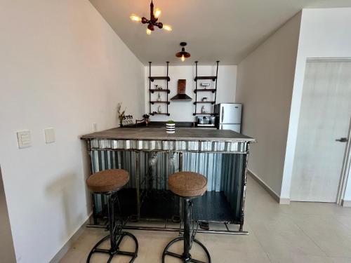 a kitchen with a bar with two stools at Industrial stylish 3-br. apartment & city views in front of Parque Fundidora & Arena Mty in Monterrey