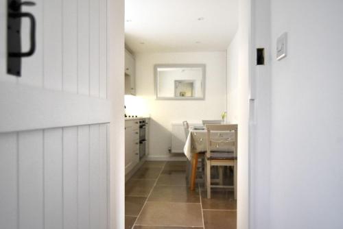 萊姆里吉斯的住宿－1 Lymbrook Cottages，厨房以及带桌子和白色墙壁的用餐室。