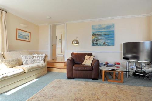 a living room with a couch and a tv at The Portland Suite in Lyme Regis