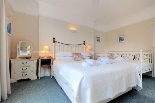 a bedroom with two beds and a dresser and a mirror at The Portland Suite in Lyme Regis