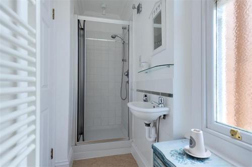 a white bathroom with a sink and a shower at The Portland Suite in Lyme Regis