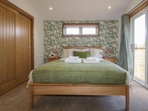 a bedroom with a large bed with a green blanket at 9 Meadow Retreat in Liskeard