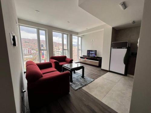 a living room with two red chairs and a refrigerator at Apartamento Nuevo con Hermosa Vista, Ubicación Perfecta in La Paz