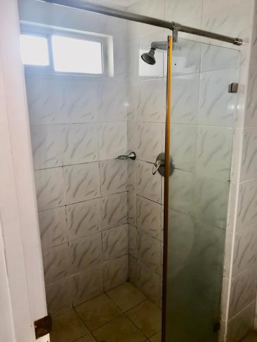 La salle de bains est pourvue d'une douche avec une porte en verre. dans l'établissement Trans International Hotel, à Nadi