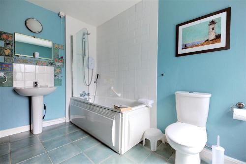 a bathroom with a tub and a toilet and a sink at Bedrock in Lyme Regis