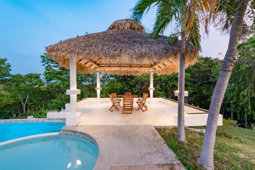 a pavilion with a table and chairs next to a swimming pool at 1053 - Villa Anka in Tangolunda