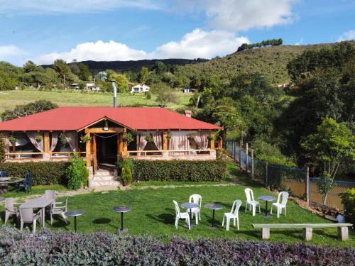 a house with white chairs and tables in the grass at Chalet Amadeus Guatavita in Guatavita