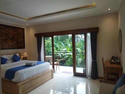een slaapkamer met een bed en een glazen schuifdeur bij Cahaya Guest House in Ubud