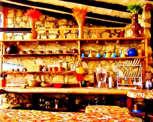 una cocina con una pared de piedra con estanterías con platos en Sidarta, Casa Grande - Bella Casita, Casa Pequeña, en Chocontá