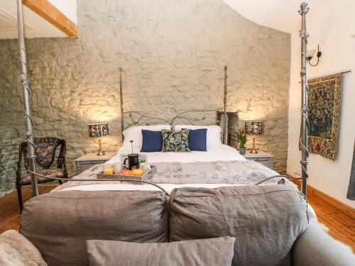 a bedroom with a bed and a stone wall at Otters Holt in Great Asby
