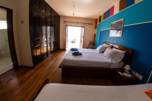 1 dormitorio con 2 camas y pared azul en Guest House Montanha, en Mindelo