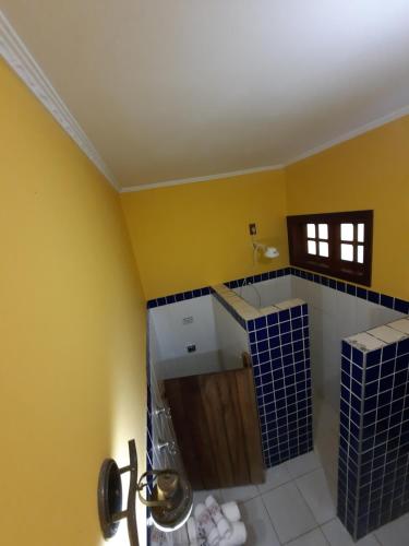 een badkamer met gele muren en blauwe tegels op de muur bij Pousada Por do Sol in Serra Negra