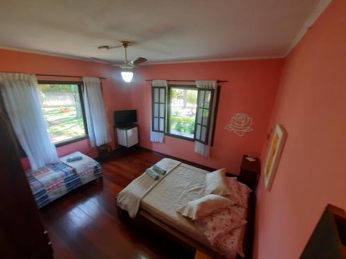 a bedroom with orange walls and a bed and two windows at Pousada Por do Sol in Serra Negra