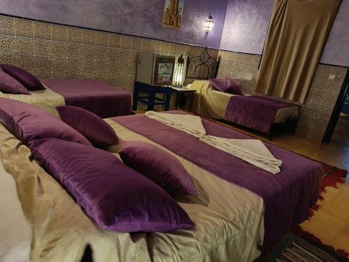 a hotel room with two beds with purple pillows at Hotel Riad Ali in Merzouga