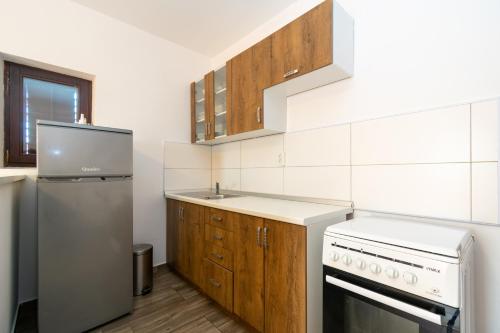 a kitchen with white appliances and wooden cabinets at Apartments by the sea Mandre, Pag - 3084 in Kolan