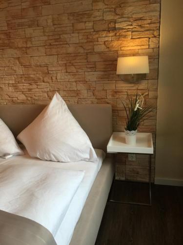 a bedroom with a bed and a table with a lamp at Hotel Achilles in Kirkel