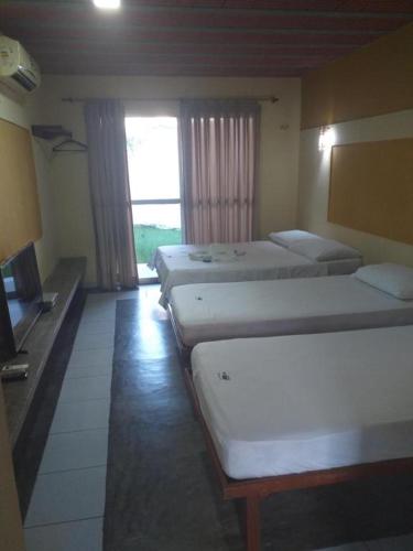 a room with four beds and a television in it at Pousada Nosso Recanto Camocim in Camocim