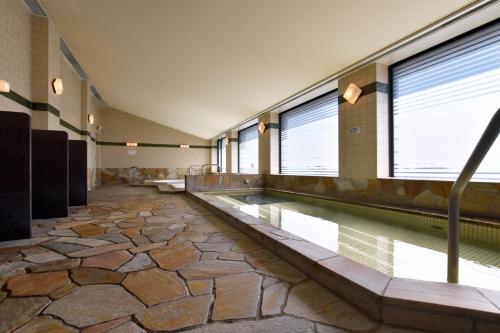 an indoor pool with a stone floor and a swimming poolvisor at Okura Chiba Hotel in Chiba