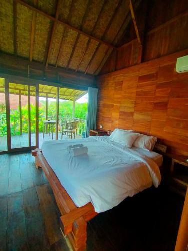 a bedroom with a large bed with a wooden wall at Green Bowl Beach Villas in Uluwatu