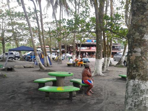 a man sitting on a picnic table in a park at Cabinas Manzanillo Caribe in Manzanillo
