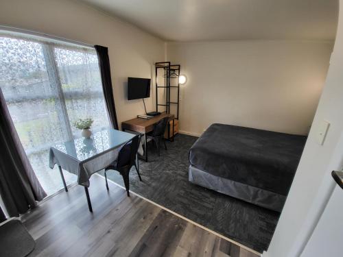 a bedroom with a bed and a table and a window at Rockfield Motel in Auckland