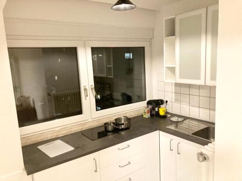 a kitchen with white cabinets and two large windows at Taunus top floor Balkon Altstadt Messe Frankfurt 10 min in Oberursel