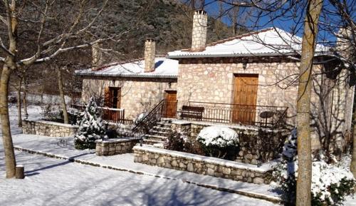a stone house in the snow with snow on it at Andrea Sofi Guesthouse in Dhimitsana