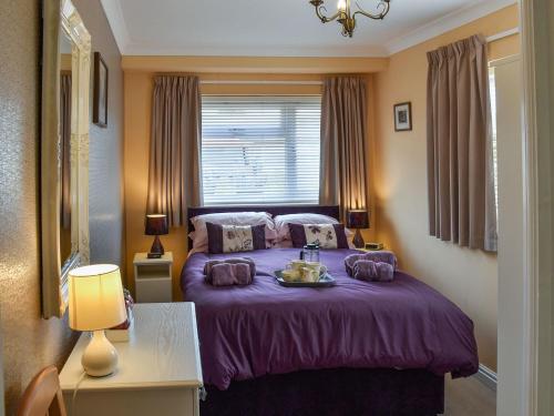 a bedroom with a purple bed with a window at Tabusintac in Heacham