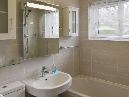 a bathroom with a sink and a tub and a mirror at Tabusintac in Heacham