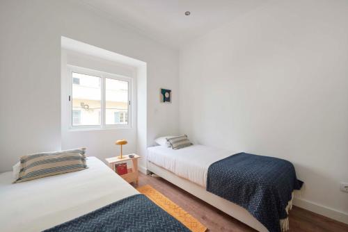 2 camas en una habitación blanca con ventana en Spacious & Light-Filled 4BR Apartment By TimeColer, en Amadora
